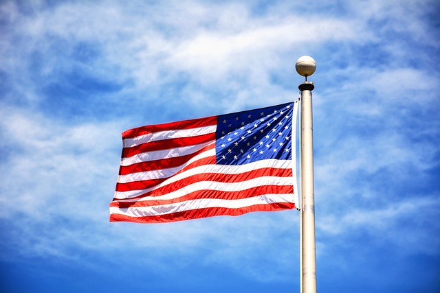 American flag flying in the wind to the left with a blue sky in the background